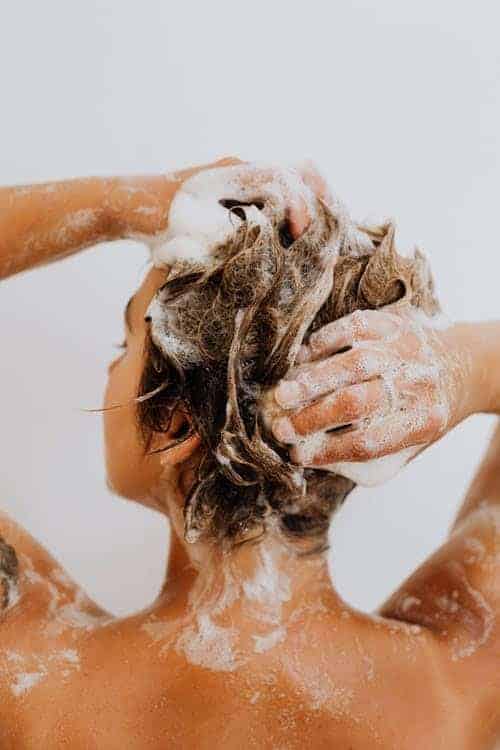 A woman uses a CBD shampoo in the shower.