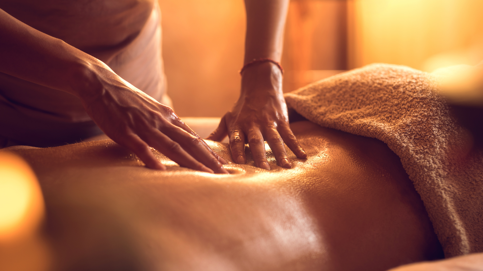 Close-up of hands applying massage oil during a relaxing back massage.