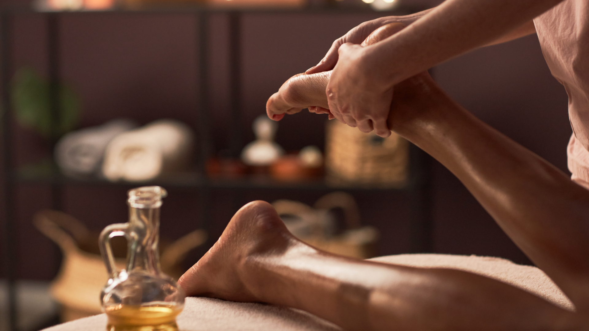 Person receiving a foot massage with natural massage oil in a spa setting.